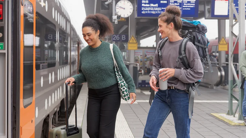 Zwei Frauen steigen an einem Bahnsteig in einen Regionalverkehrszug