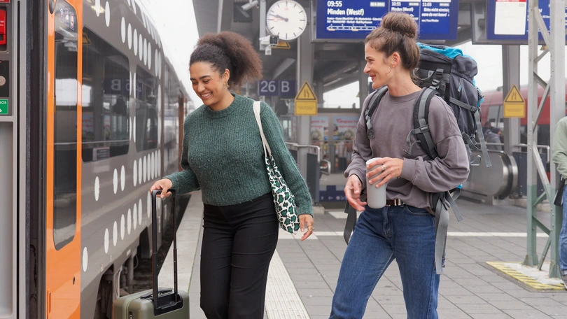 Zwei Frauen steigen an einem Bahnsteig in einen Regionalverkehrszug