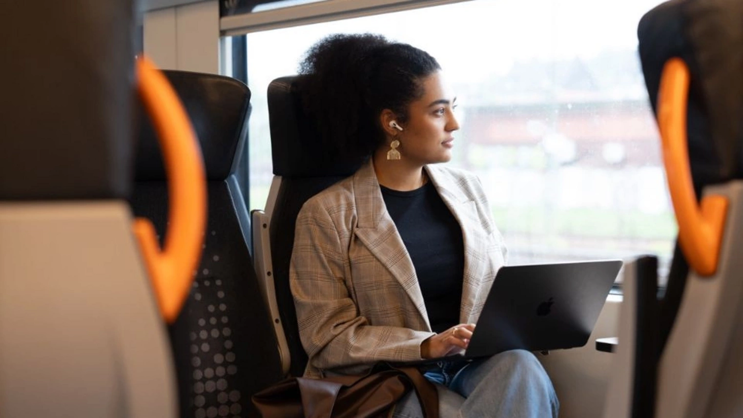 Frau mit Laptop in der Bahn.