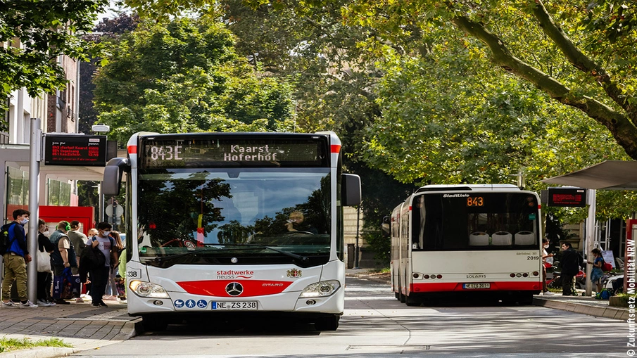 Zwei Busse an Haltestellen, einsteigende Fahrgäste
