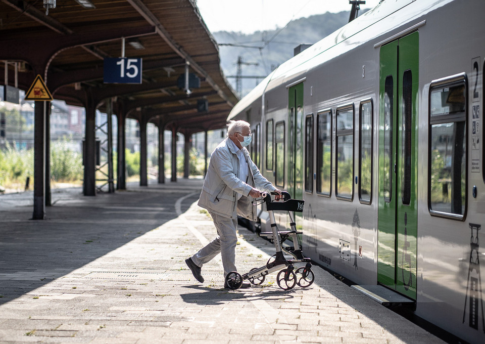 Ein Senior mit Rollator steigt in einen Zug