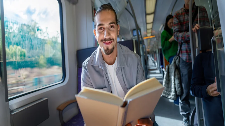 Ein junger Mann liest ein Buch in der S-Bahn.