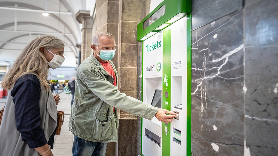 Mann und Frau bedienen einen Ticketautomaten