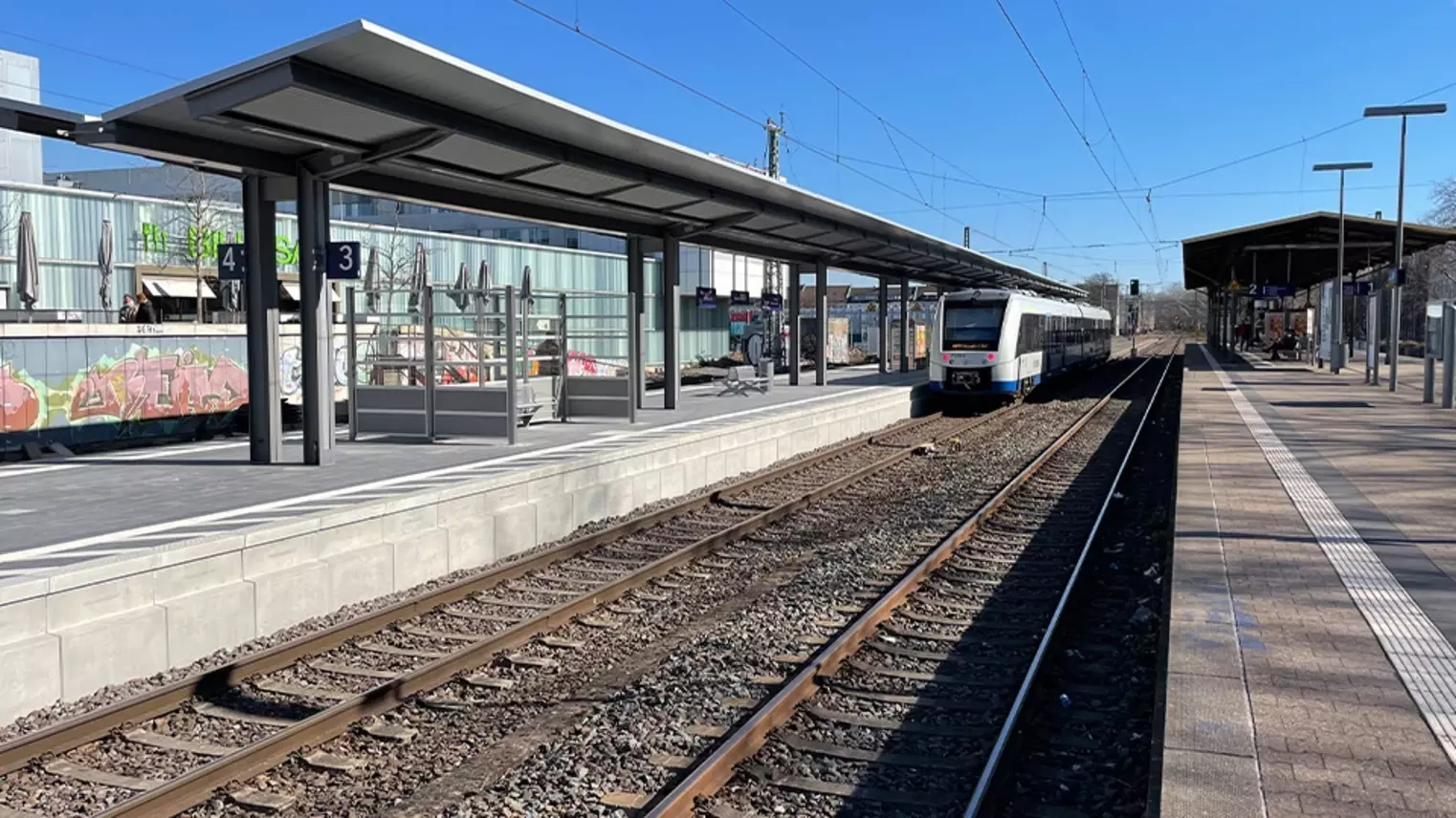 Der neue Regionalbahnsteig mit Wartebereich und haltendem Zug an Gleis 3