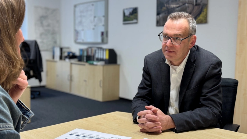 Ein Mann (Georg Seifert) sitzt zum Interview an einem Tisch gegenüber von einer Frau