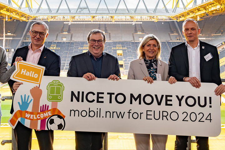 Eine Personengruppe um NRW-Verkehrsminister Oliver Krischer hält ein Schild mit der Aufschrift "Nice to move you! mobil.nrw for EURO 2024" hoch