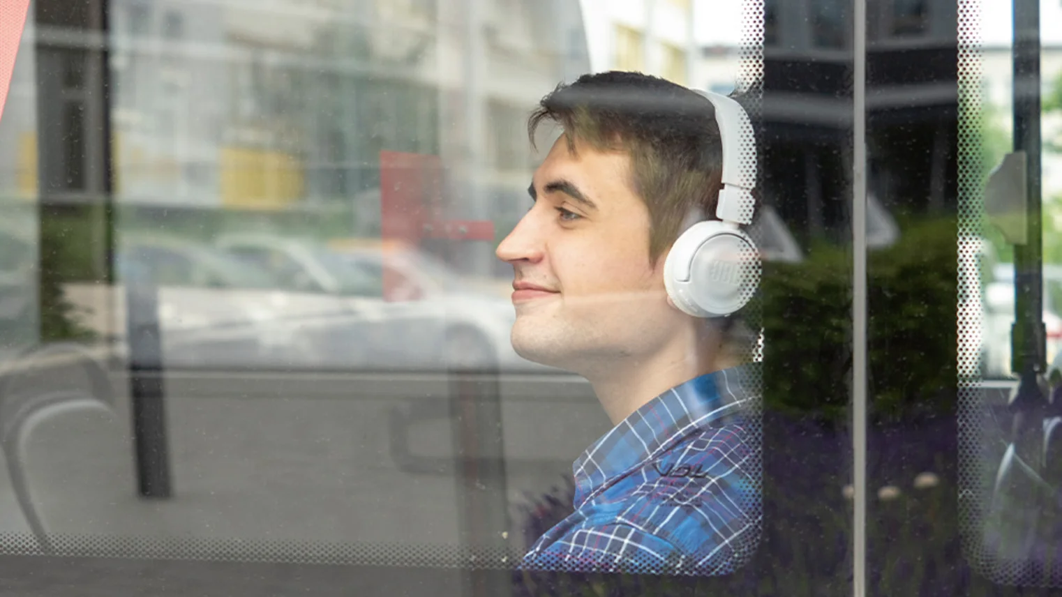 Ein junger Mann sitzt im Bus und trägt Kopfhörer