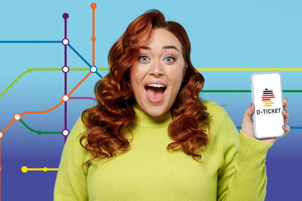 Eine Frau, die begeistert ihr Handy mit dem DeutschlandTicket in Richtung Kamera hält.