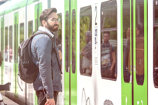 Ein junger Mann steht am Bahnsteig an der einfahrenden S-Bahn