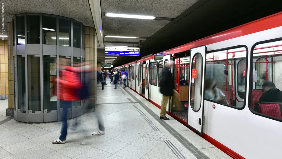 Eine unterirdische Stadtbahnhaltestelle mit Stadtbahn sowie ein- und aussteigenden Fahrgästen