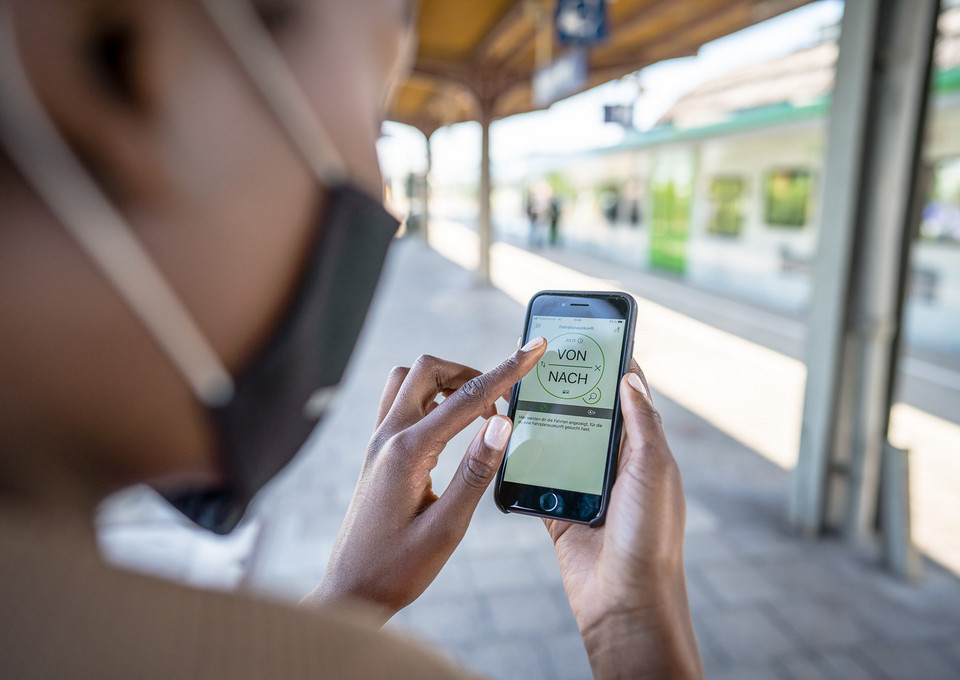 Eine Frau schaut auf die Fahrplanauskunft auf ihrem Handy