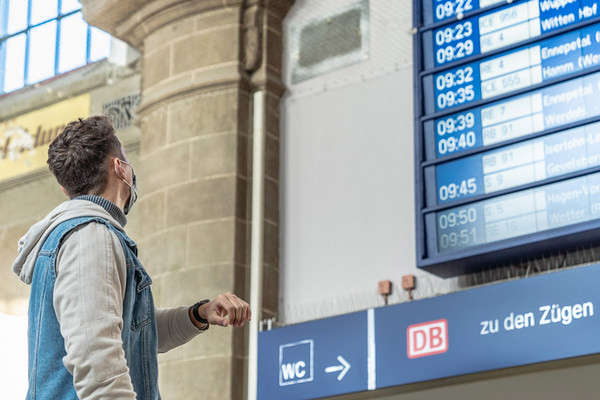 Eine Person blickt an einem Bahnhof auf einen Fahrgastinformationsanzeiger