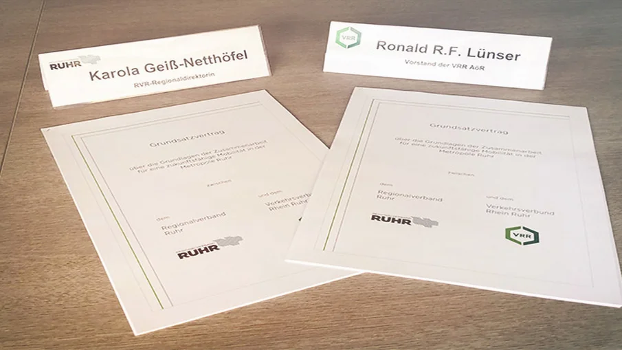 Der Grundsatzvertrag und die Namensschilder der beteiligten Akteure auf einem Tisch