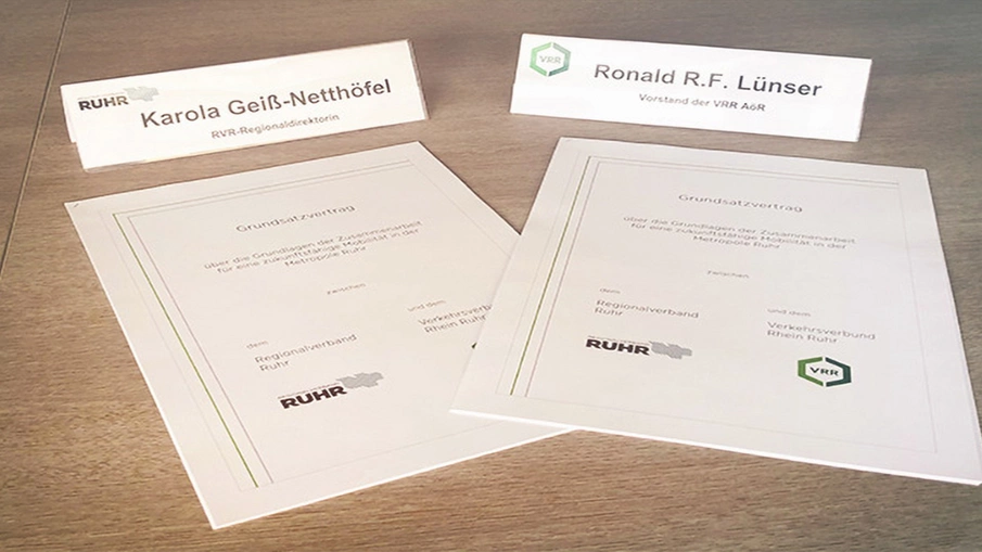 Der Grundsatzvertrag und die Namensschilder der beteiligten Akteure auf einem Tisch