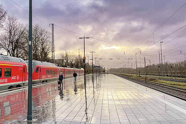 Ein regennasser Bahnsteig, an dem ein roter Regionalzug von DB Regio hält