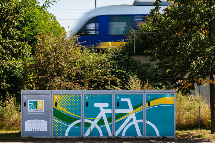 DeinRadschloss-Fahrradboxen, im Hintergrund eine grüne S-Bahn