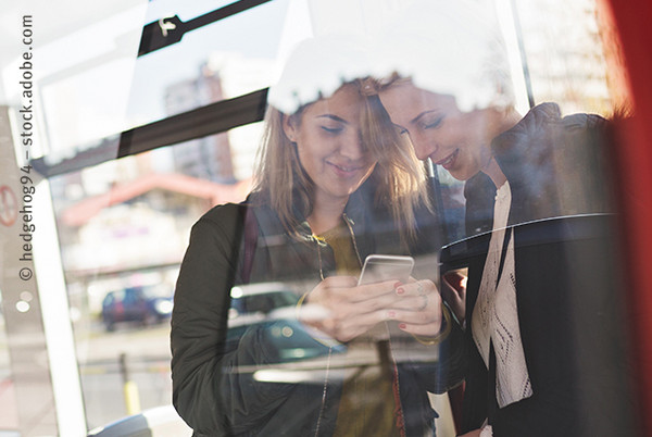 Zwei Frauen, die auf ihr Smartphone schauen.