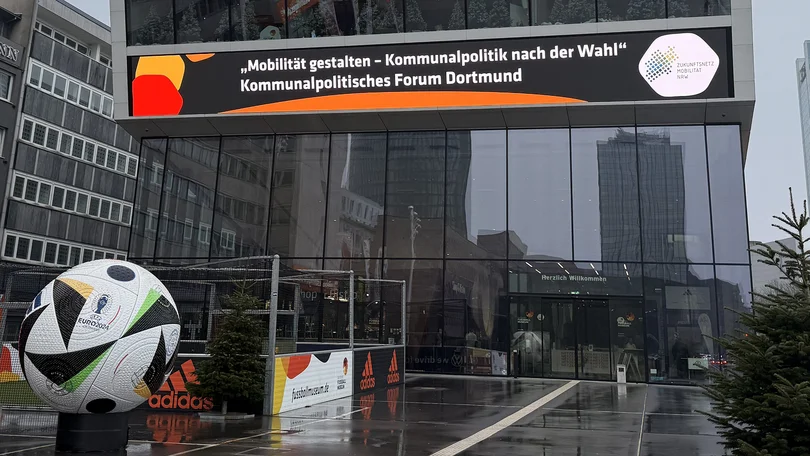Blick auf den Eingang des Deutschen Fußballmuseums, in einem Banner zu lesen ist "Mobilität gestalten - Kommunalpolitik nach der Wahl | Kommunalpolitisches Forum Dortmund"