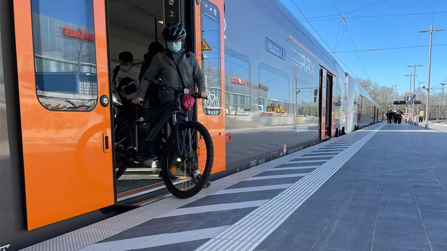 Person steigt niveaugleich aus einem RRX-Zug am neuen Regionalbahnsteig aus