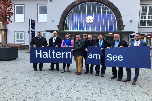Vertreter:innen des Landes Nordrhein-Westfalen, DB, VRR und Stadt Haltern am See halten gemeinsam ein Bahngleis-Schild in den Händen
