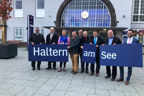 Vertreter:innen des Landes Nordrhein-Westfalen, DB, VRR und Stadt Haltern am See halten gemeinsam ein Bahngleis-Schild in den Händen