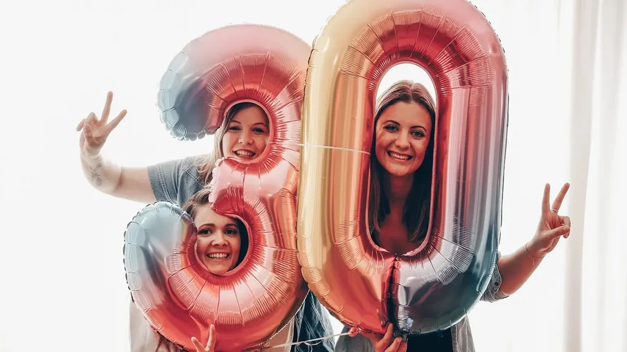 Drei Freundinnen stehen Motiv mit aufblasbaren Ballons in Form der Zahl 30.