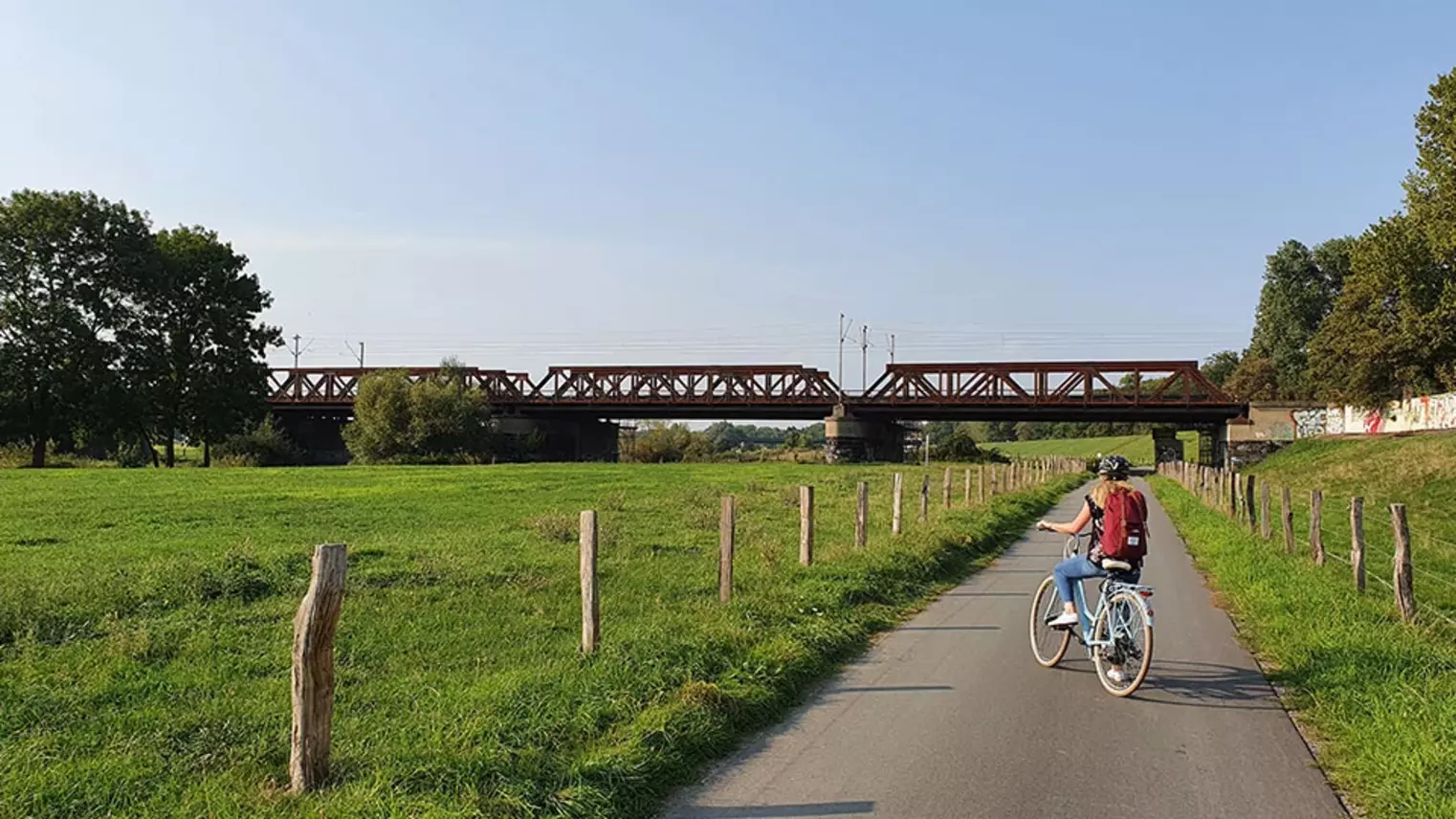 Eine Frau fährt auf einem Fahrrad einen Radweg entlang