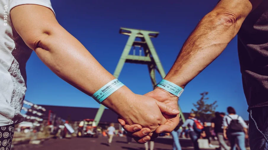 Ein händchenhaltendes Paar läuft auf einen Förderturm zu