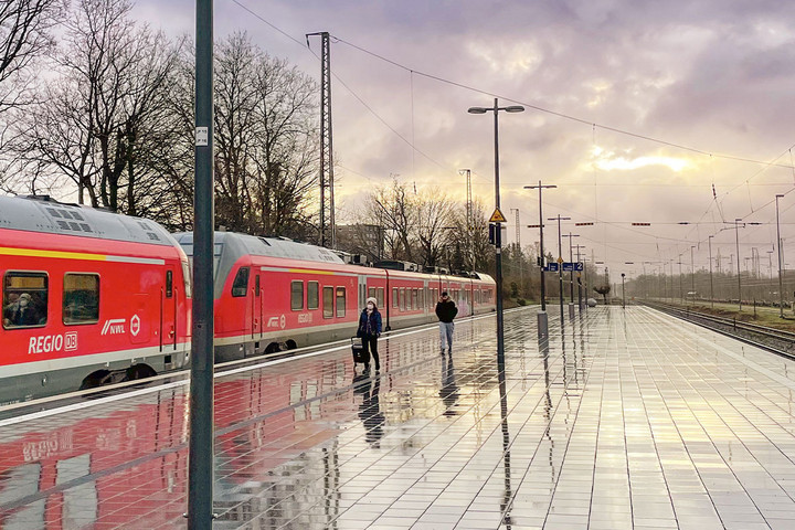 Ein regennasser Bahnsteig, an dem ein roter Regionalzug von DB Regio hält