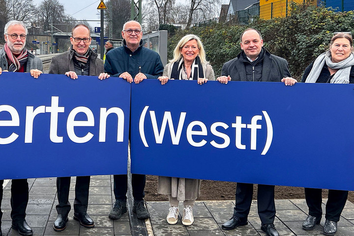 Teilnehmer*innen der feierlichen Eröffnung halten ein Schild mit der Aufschrift "Herten (Westf)" hoch