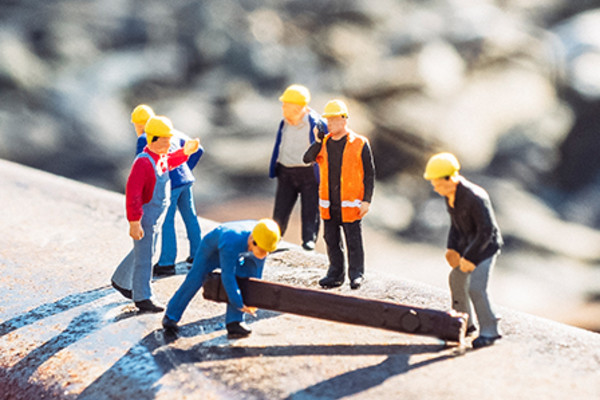 Miniaturfiguren als Baustellen-Mitarbeiter, die am Gleis arbeiten