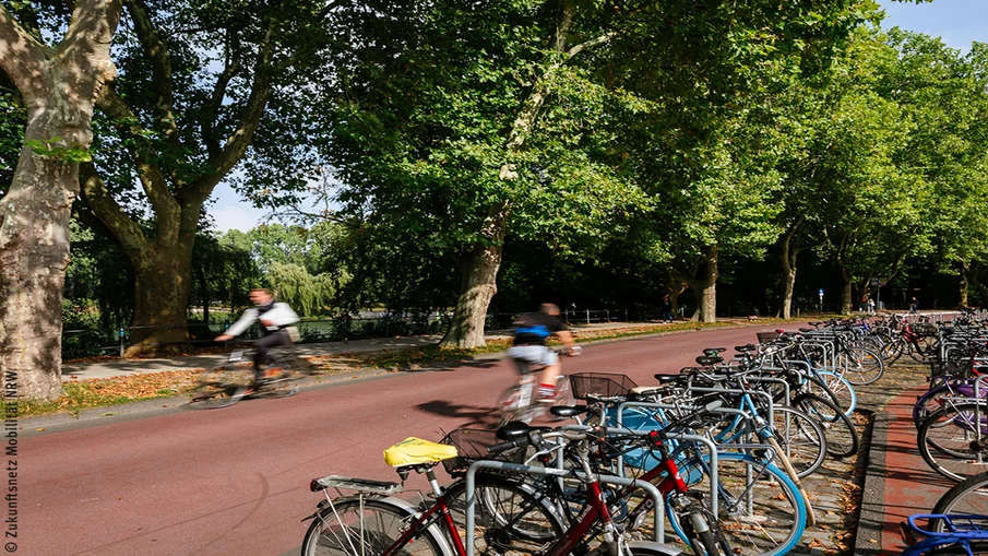 Sitzgelegenheiten am Straßenrand, im Hintergrund Fahrradfahrer