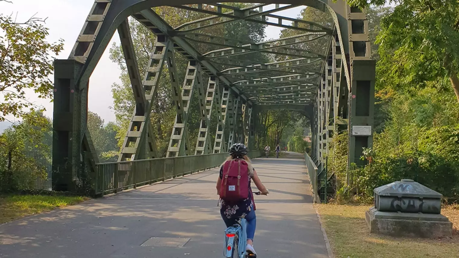 Eine Frau radelt mit ihrem Fahrrad über eine Brücke