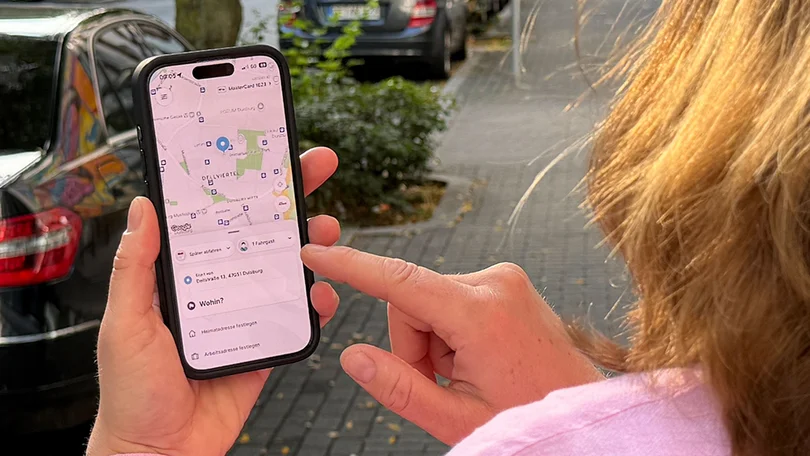 Blick über die Schulter einer Person auf ein Smartphone, im Display ist rufmobil.nrw zu sehen