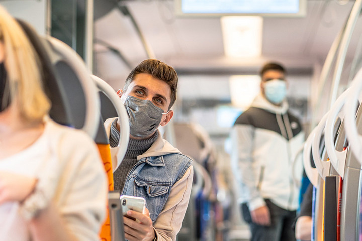 Junge Leute mit Maske sitzen in einem Zug