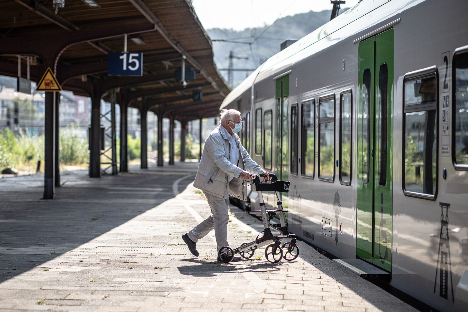 Ein Senior mit Rollator steigt in einen Zug