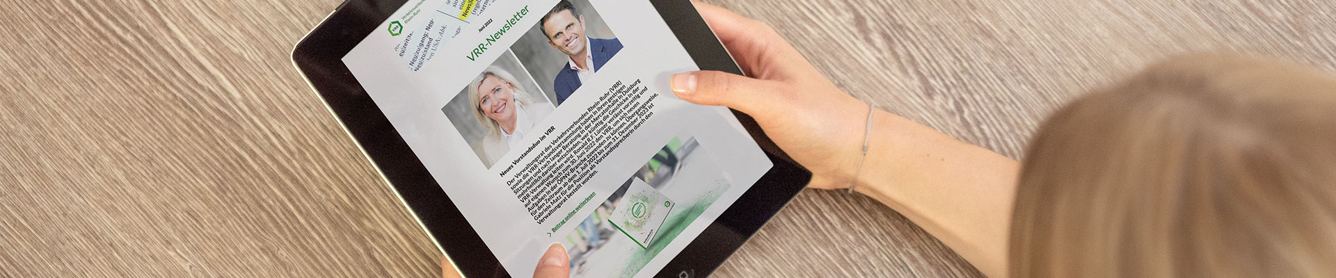 Eine Frau hält ein Tablet in der Hand. Auf dem Display ist ein Foto des neuen Vorstandsduos zu sehen.