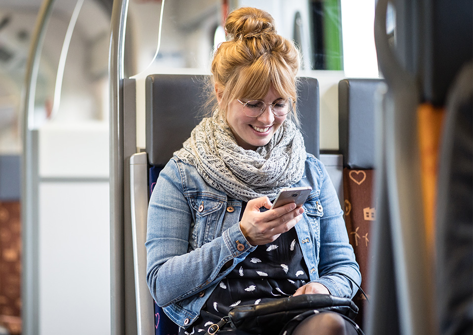 Eine Frau guckt im Zug auf ihr Smartphone