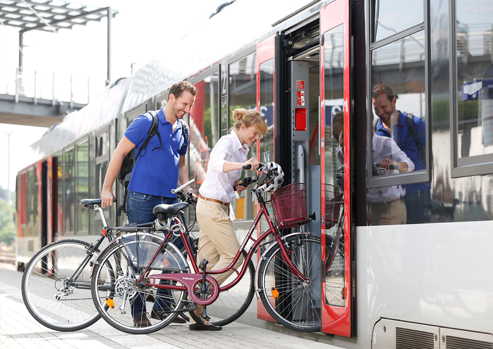 Zwei Fahrgäste steigen mit ihren Fahrrädern in einen Zug ein