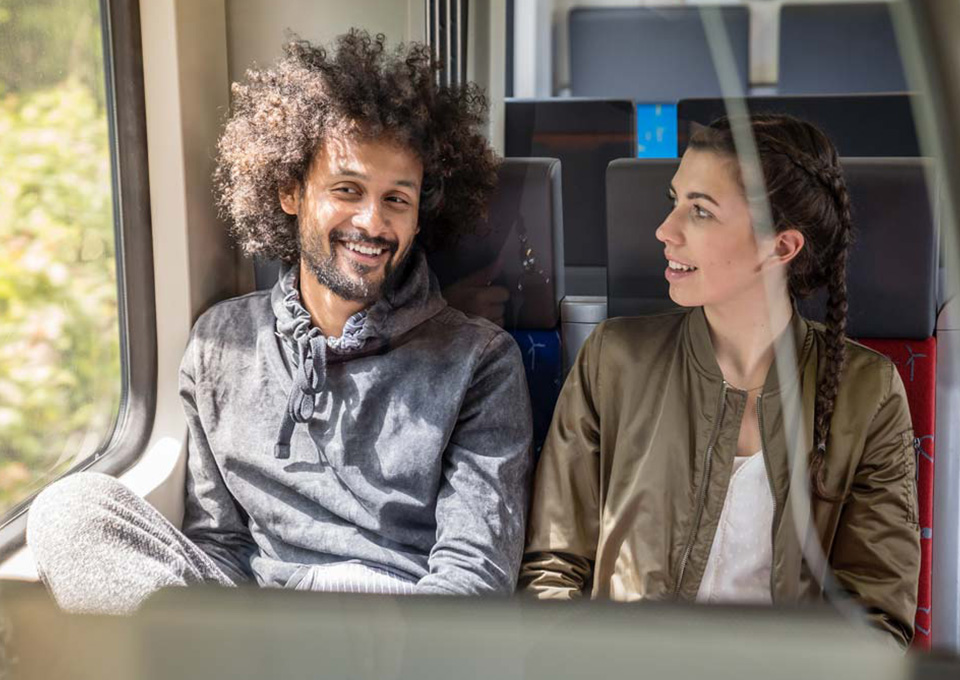 Ein junges Paar sitzt im Zug und unterhält sich