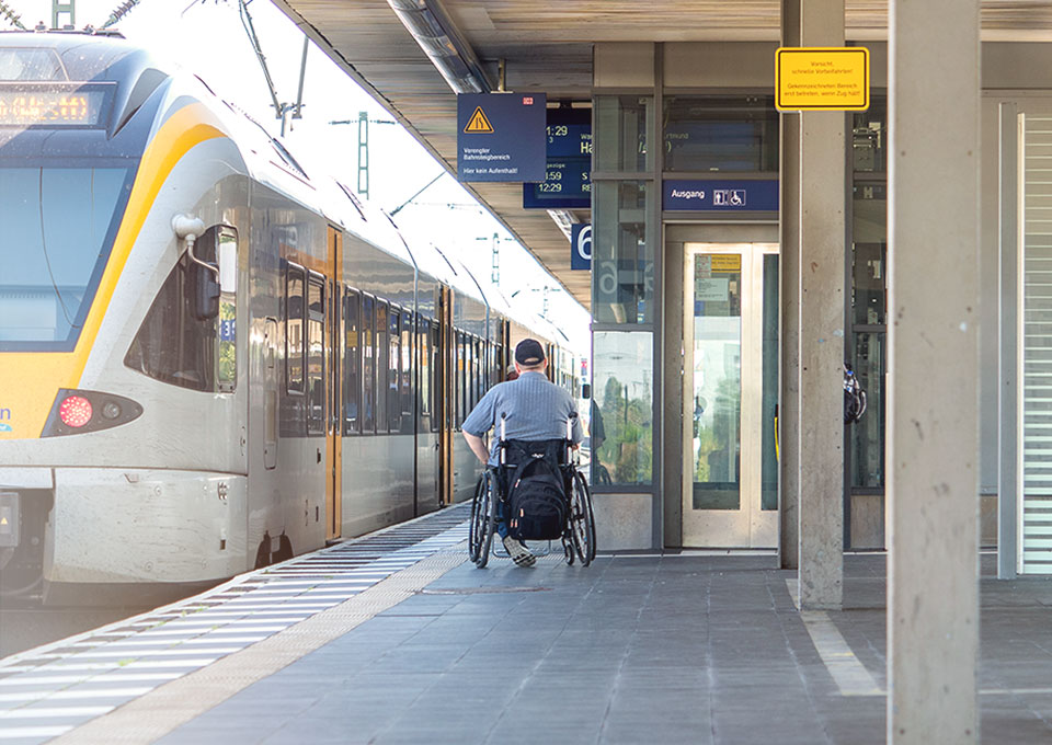 Ein Rollstuhlfahrer ist am Bahnsteig unterwegs zum stehenden Zug