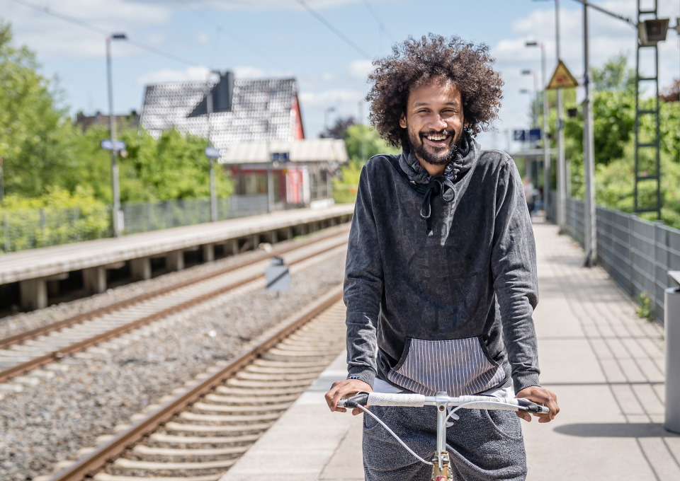 Ein junger Mann steht mit dem Fahrrad am Bahnsteig