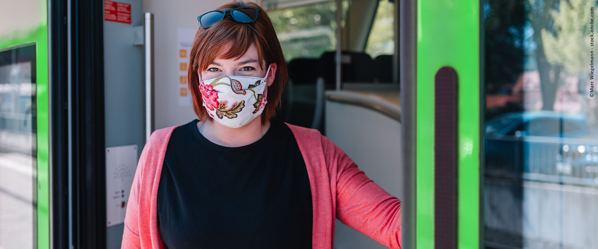 Eine Frau mit Mund-Nase-Bedeckung steht in der geöffneten Tür einer S-Bahn
