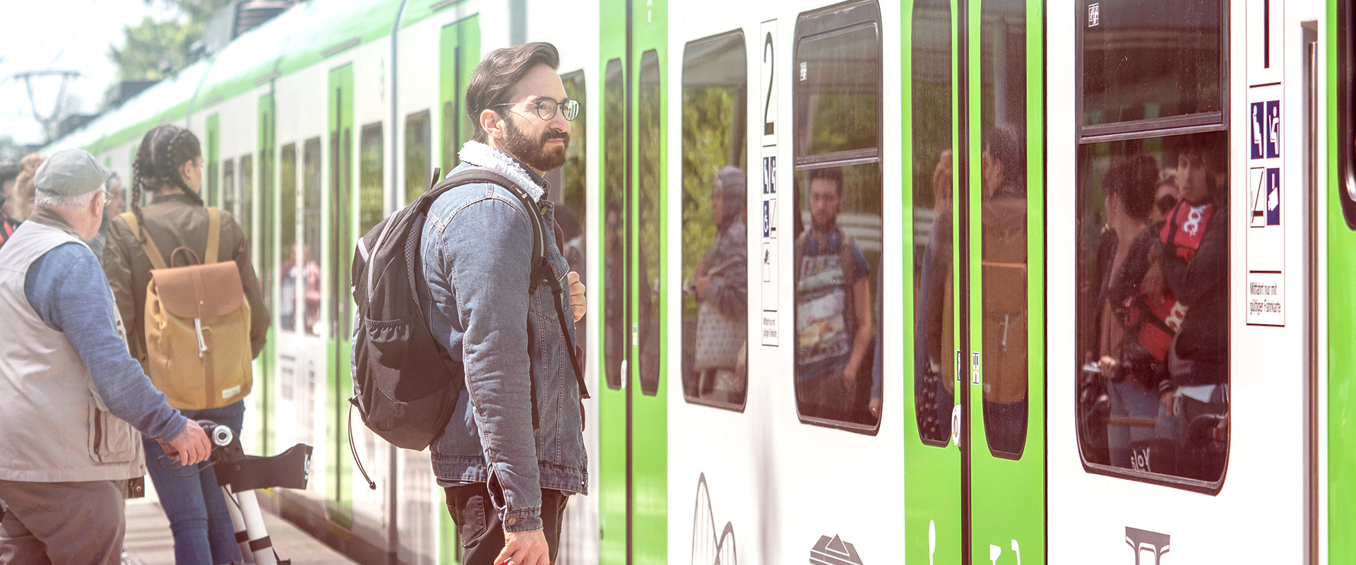 Ein junger Mann steht am Bahnsteig an der einfahrenden S-Bahn