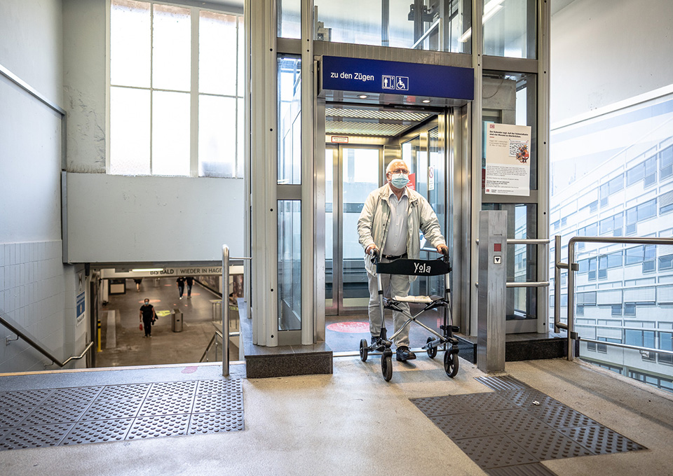 Ein Mann mit Rollator steigt aus einem Aufzug