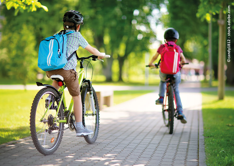 Zwei Kinder fahren auf ihren Fahrrädern den Radweg entlang