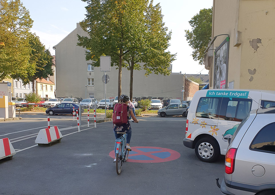 Eine Frau fährt auf ihrem Fahrrad über einen Parkplatz