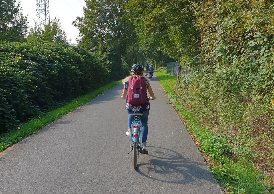 Eine Frau fährt mit ihrem Fahrrad über eine Bahntrasse