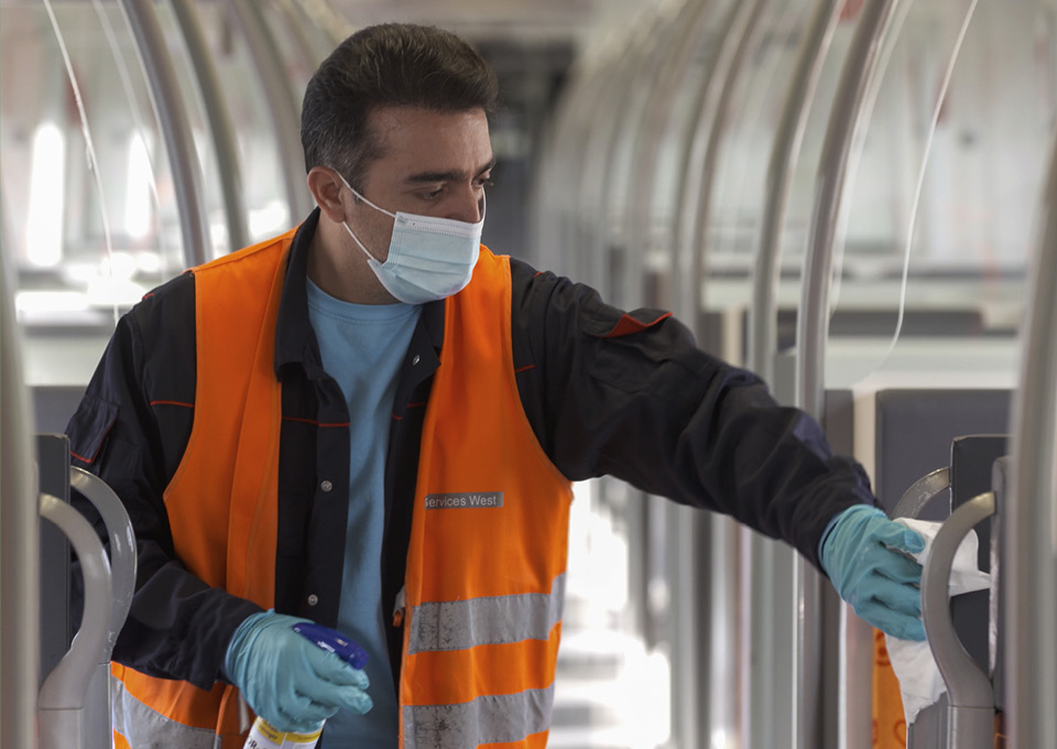 Ein Reinigungsmitarbeiter desinfiziert Kontaktflächen im Zug