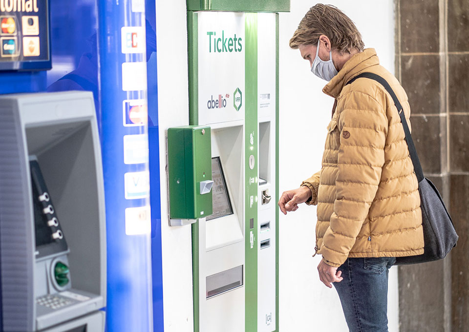 Ein Mann steht an einem Fahrkartenautomat